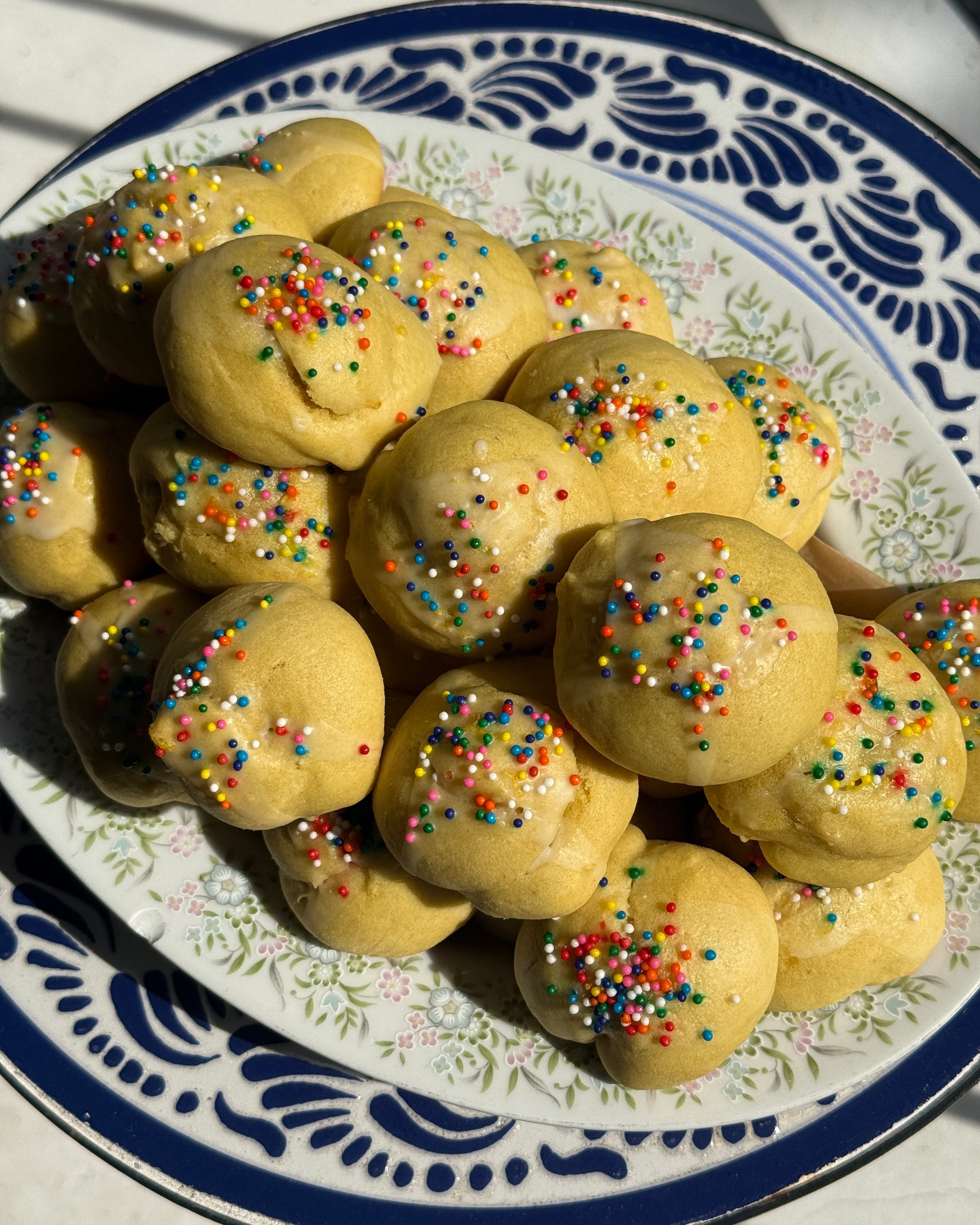 Italian anginetti cookies with rainbow sprinkles on a decorative plate