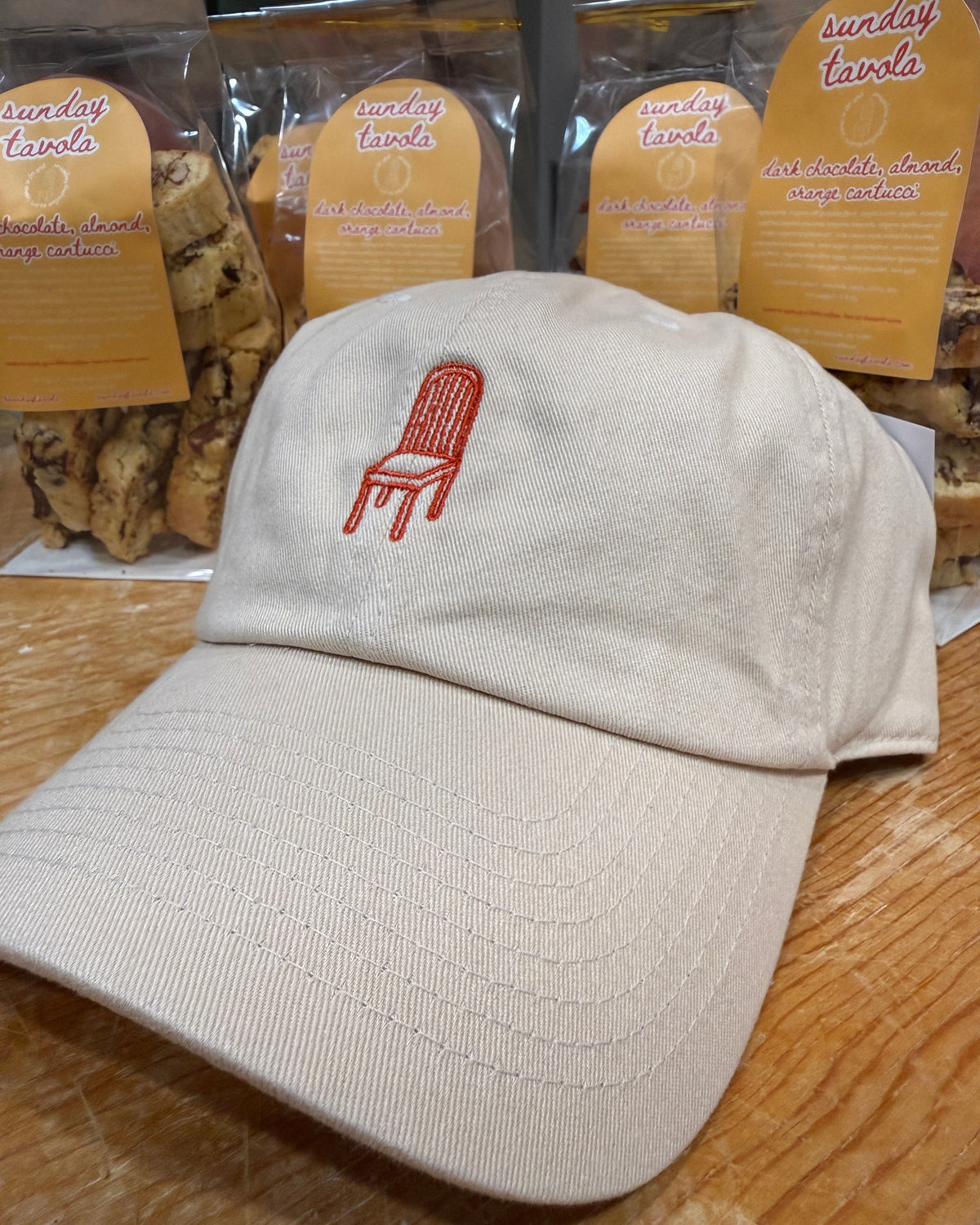 Sunday Tavola chair logo embroidered in burnt orange on an ivory baseball cap. 