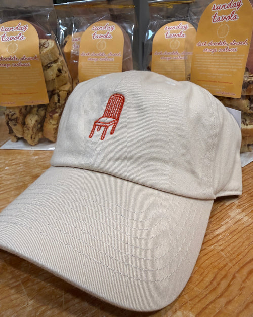 Sunday Tavola chair logo embroidered in burnt orange on an ivory baseball cap. 